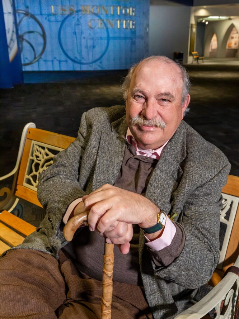 Portrait of historian and author John V. Quarstein sitting on a bench inside The Mariners' Museum.
