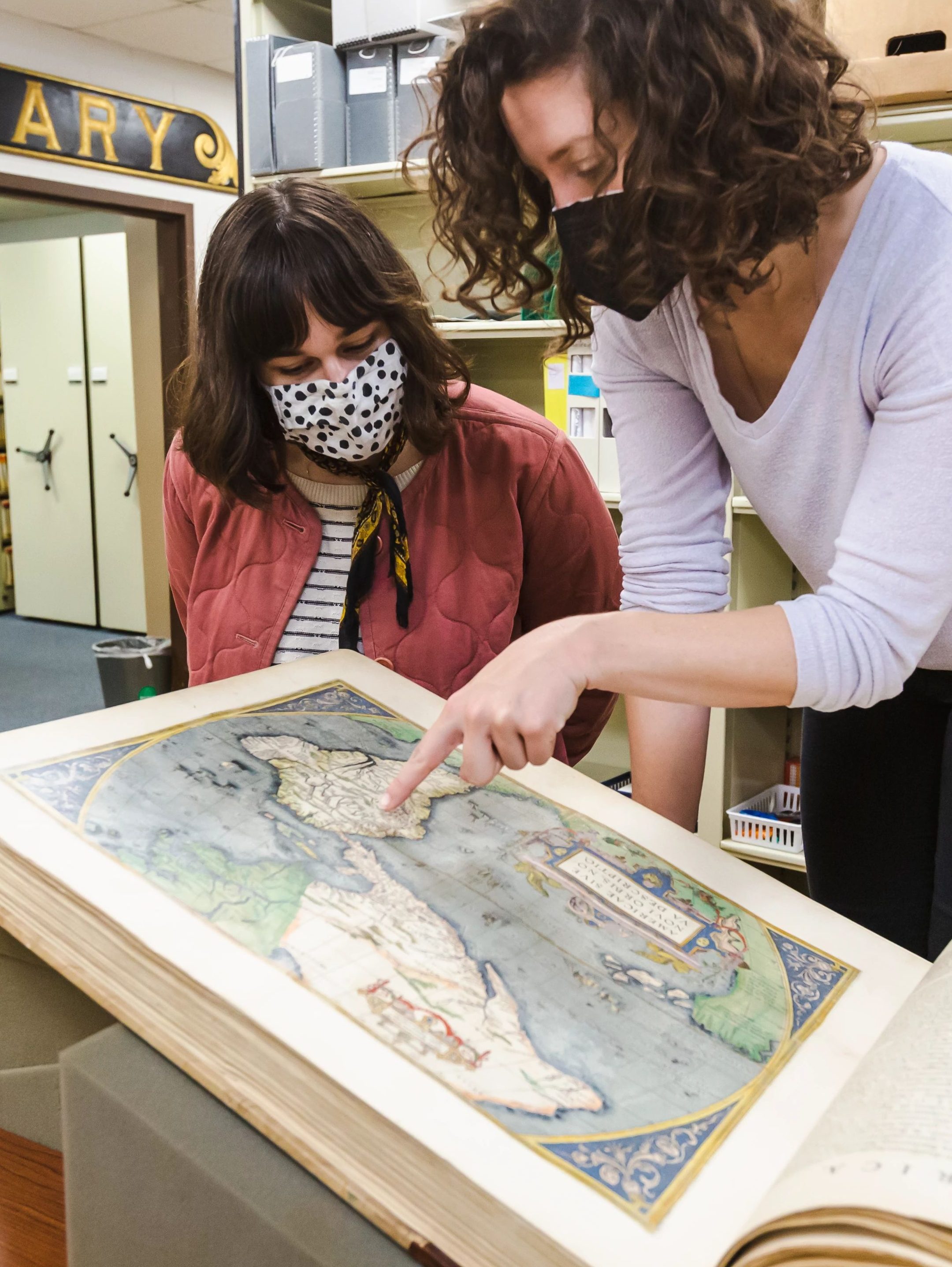 Museum educator Jennifer Hackney showing a guest a cool point on a world atlas.