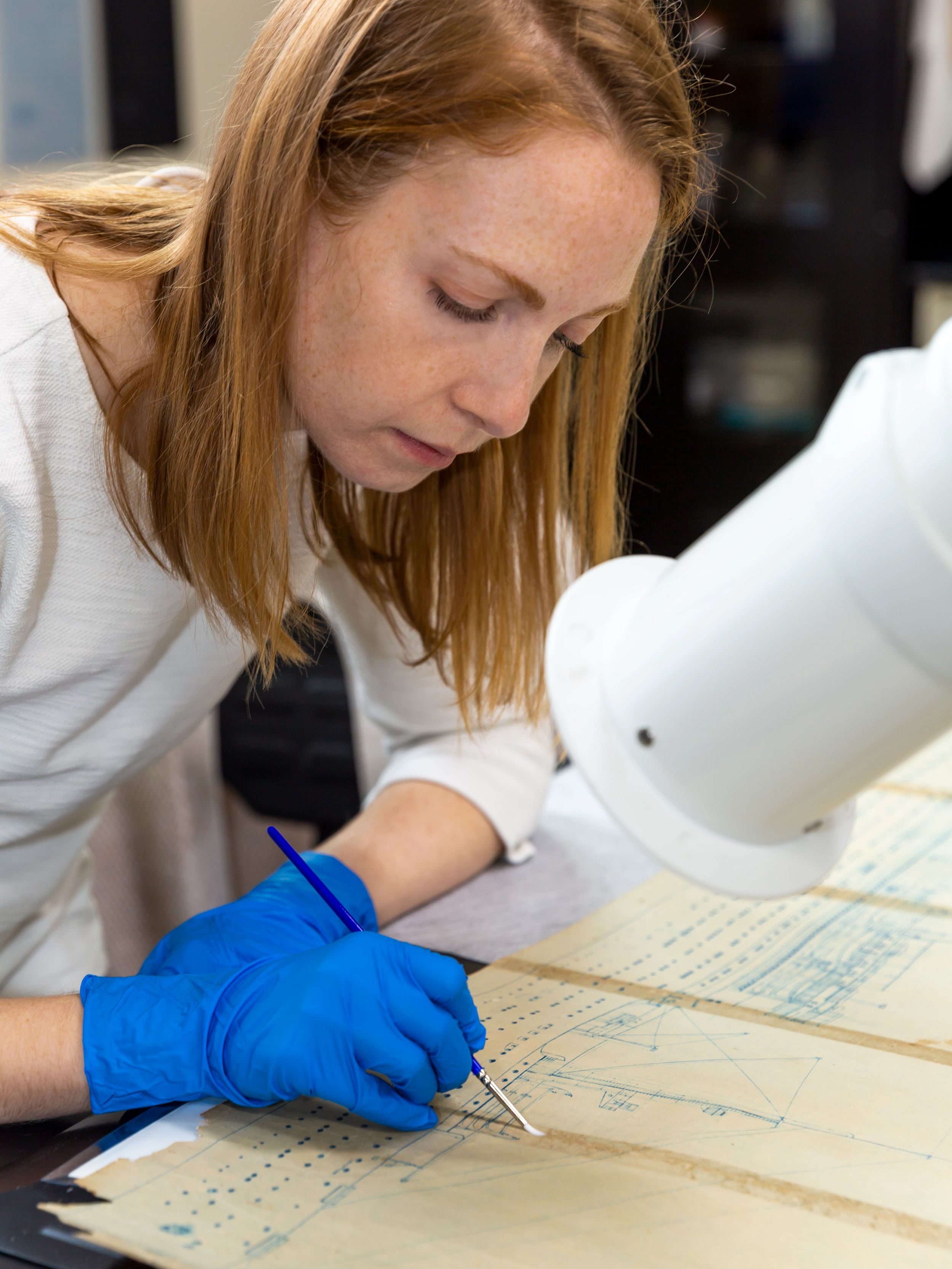 Paper Conservator Emilie Duncan applying conservation treatment to an artifact.