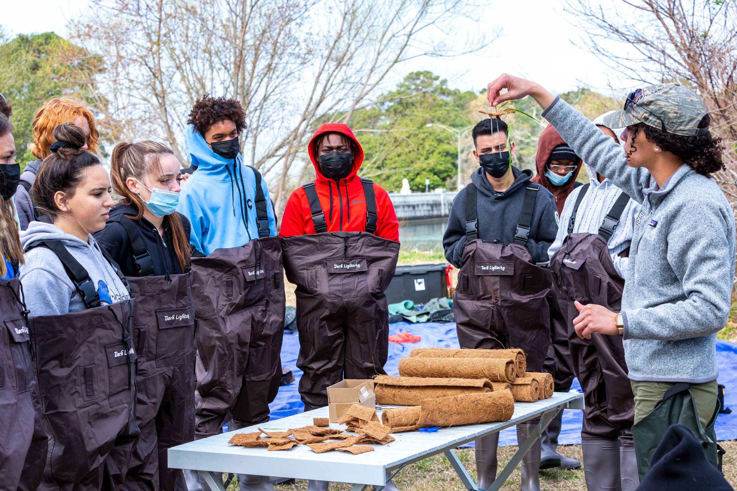 Group of students watch demonstration of how to plant eelgrass. 