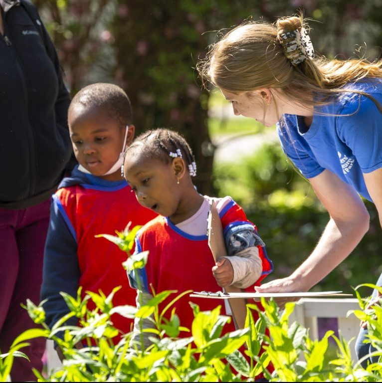 Museum educator talks to two children in the pollinator garden.