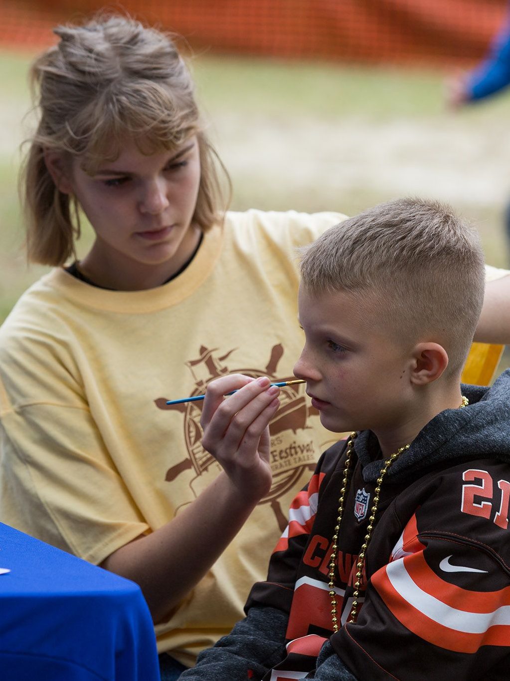 Junior volunteer painting boy's face.