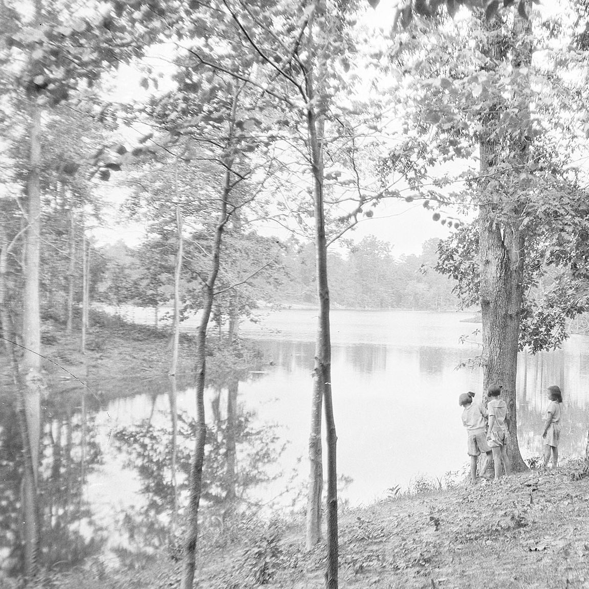 black and white image of 3 people standing on the shore of Mariners' Lake