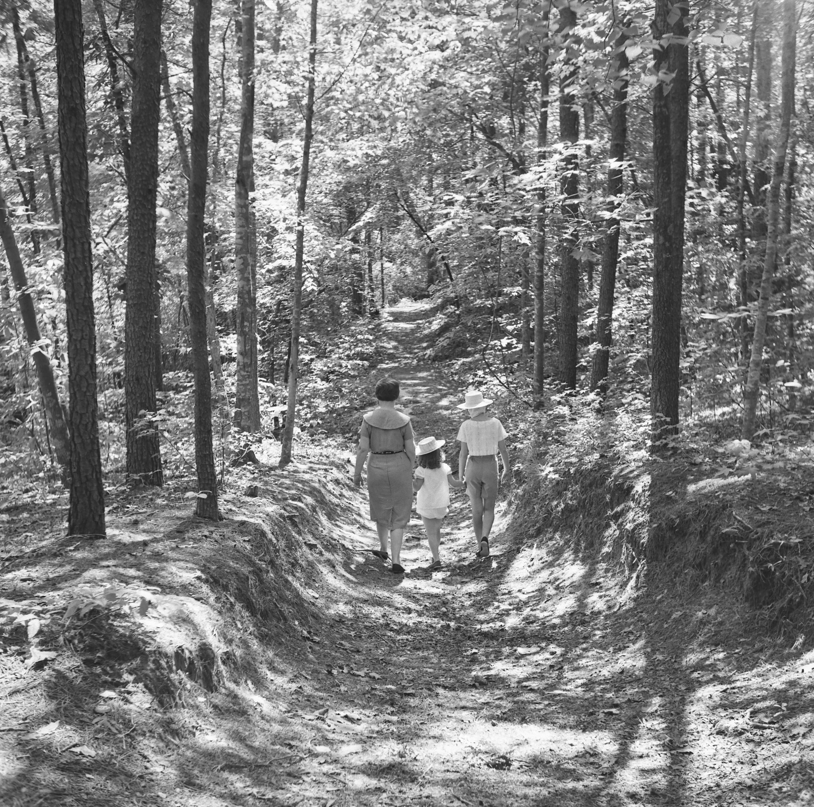 Black and white image of a woman walking with two children on the Noland Trail.