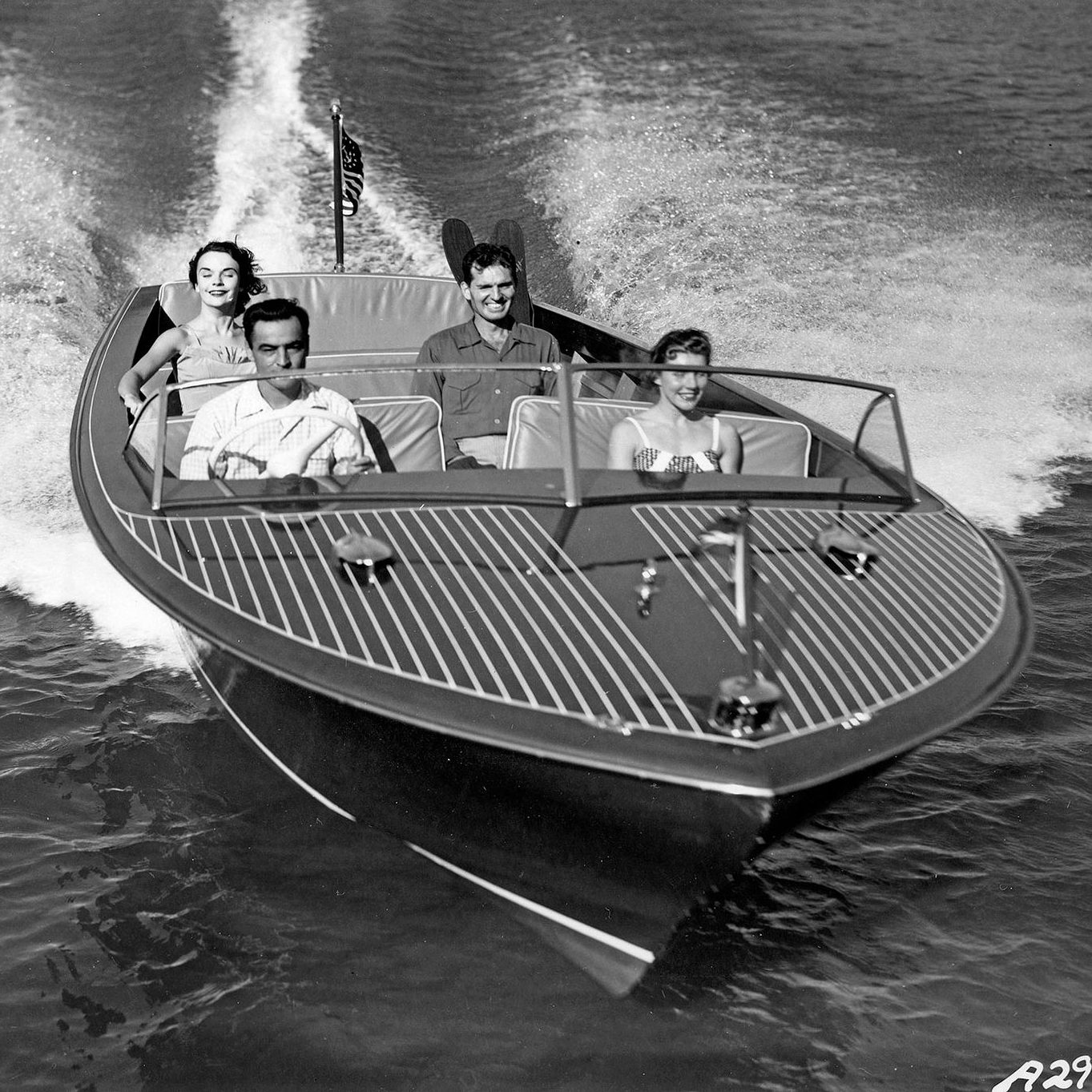 black and white image of two men and two women on a Chris-Craft boat.