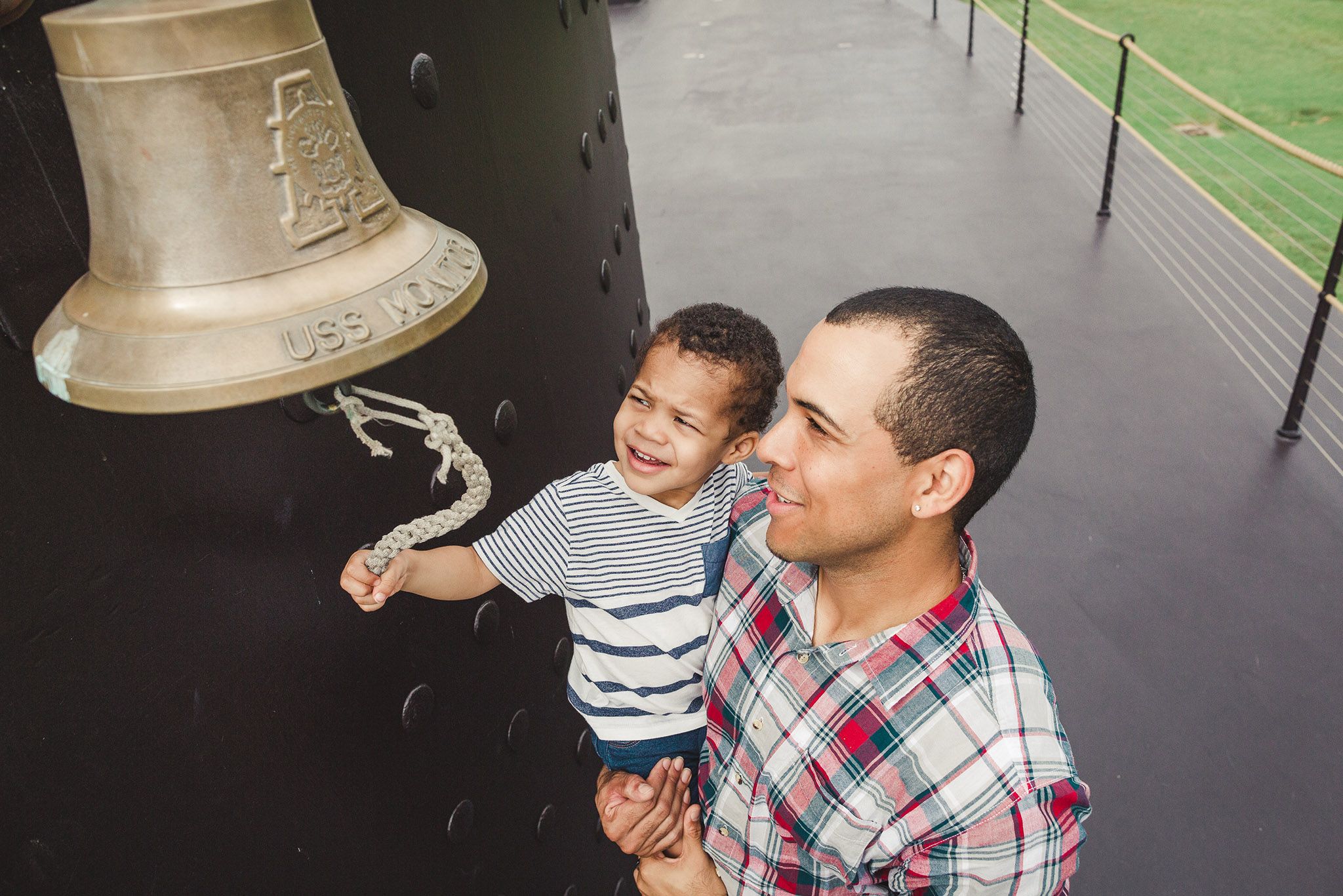Father and son standing on the USS Monitor replica. The little boy is ringing Monitor's bell.