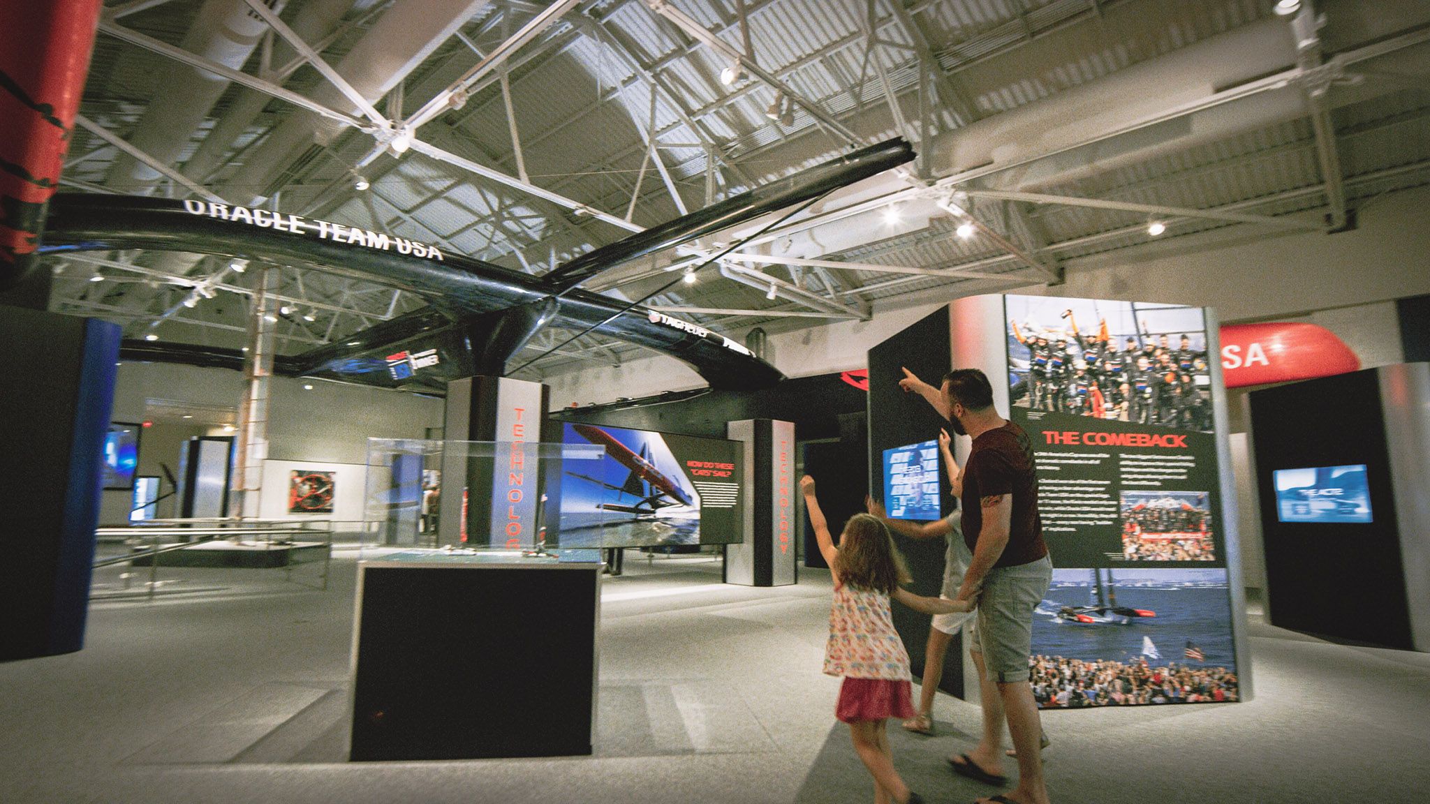 Dad and two daughters walking through the Speed and Innovation gallery.