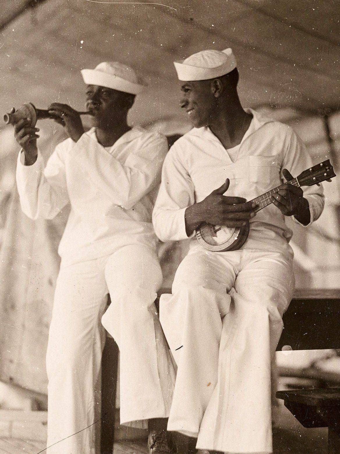 Black sailors in dress whites uniform playing music.