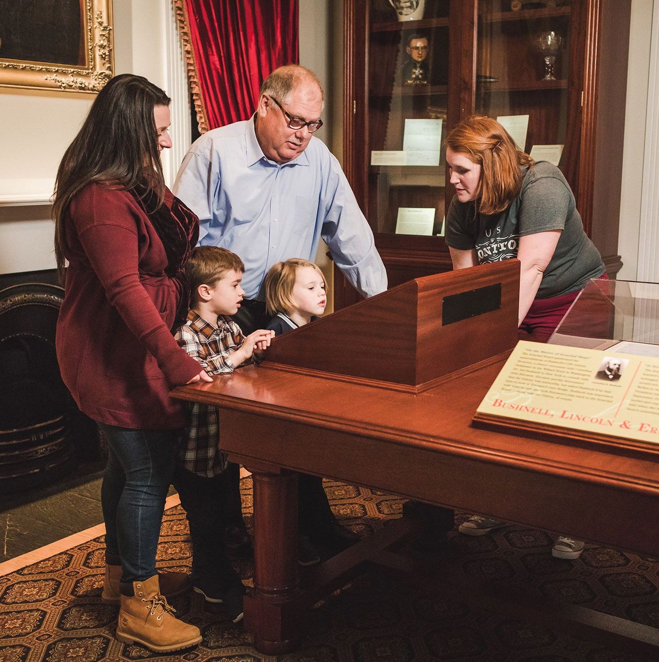 three adults and two children stand around gallery display.