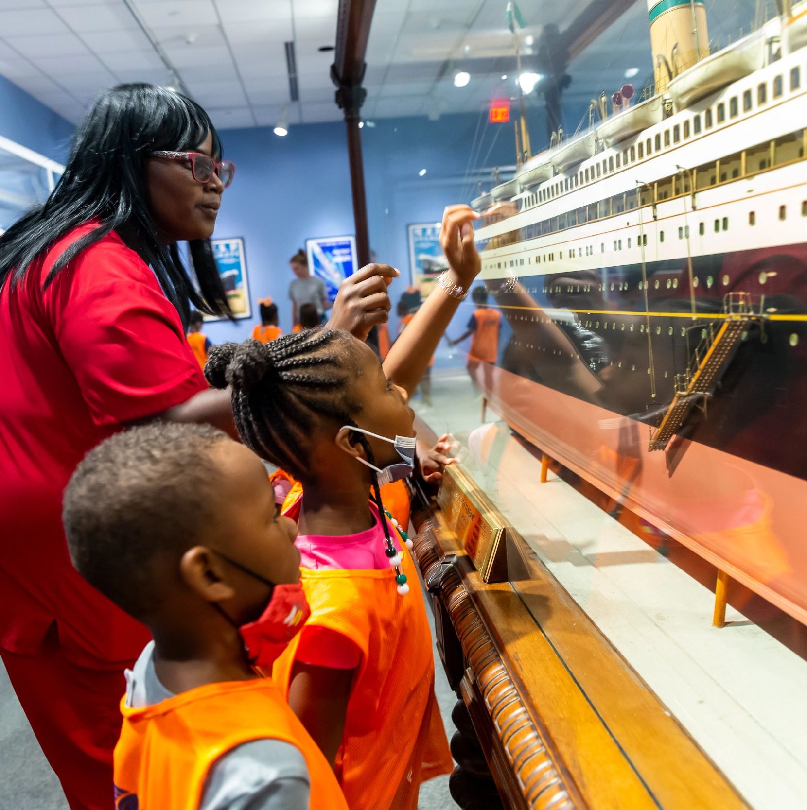 Adult and two children look at a ship model.