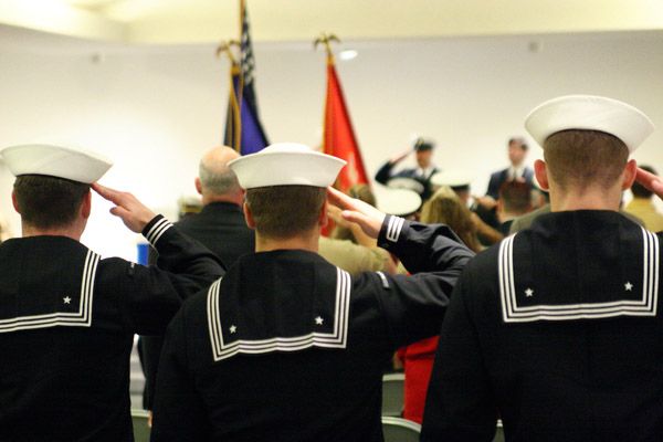 Back of 3 sailors saluting