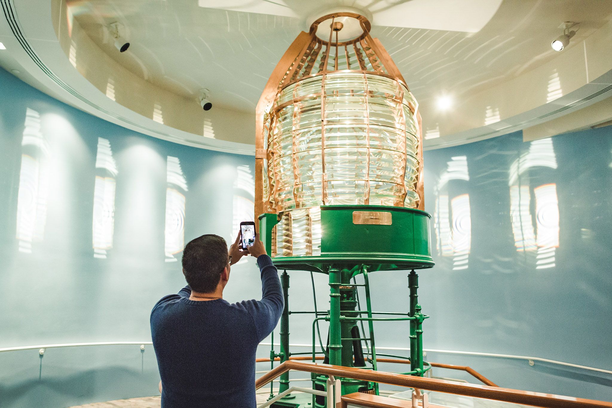 Man taking a photo of lighthouse lens with his phone.