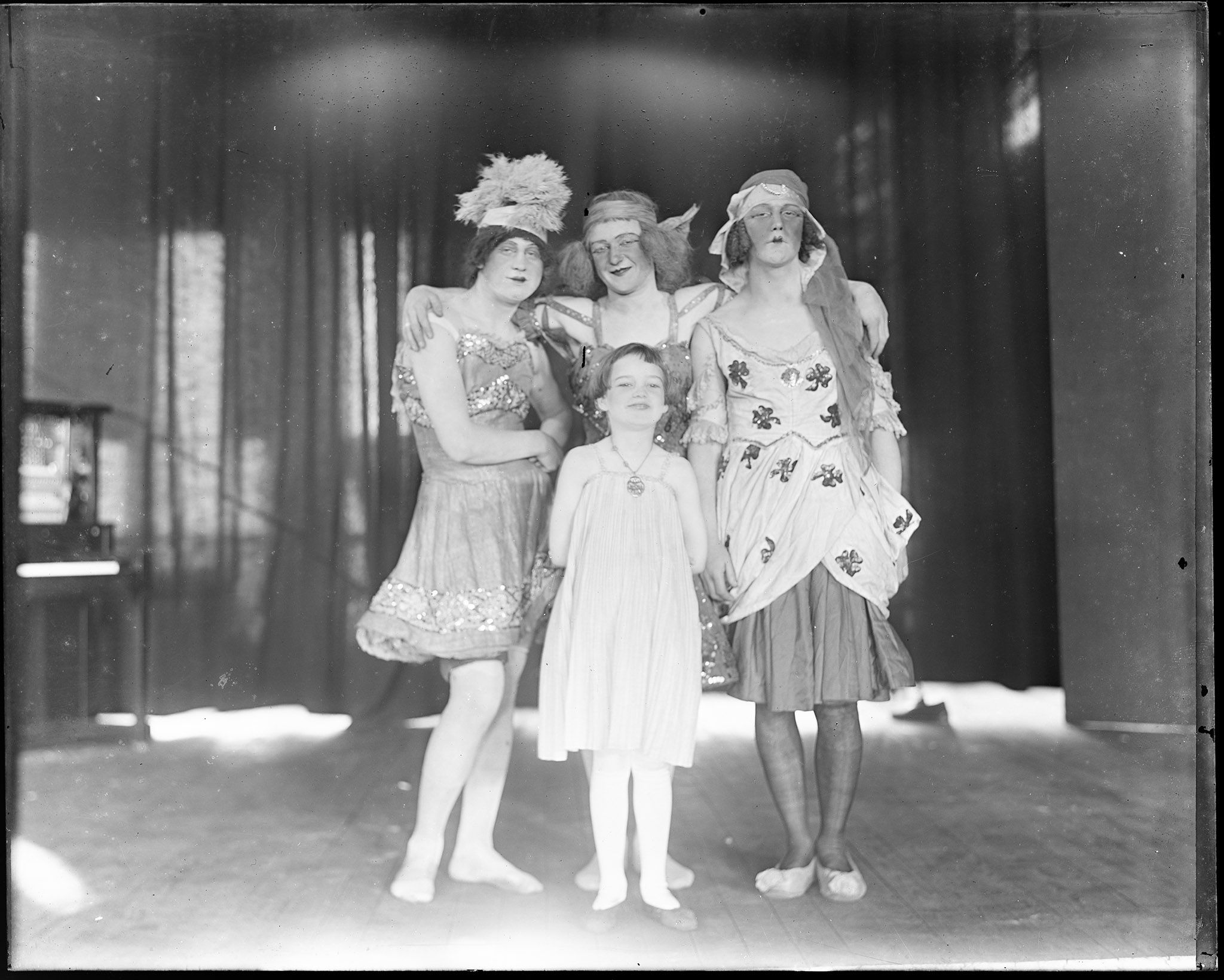 A trio of soldiers in drag pose for a picture with a child attendee.