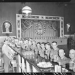 Discharged soldiers sitting along the counter, beers in hand, smiling for the camera.