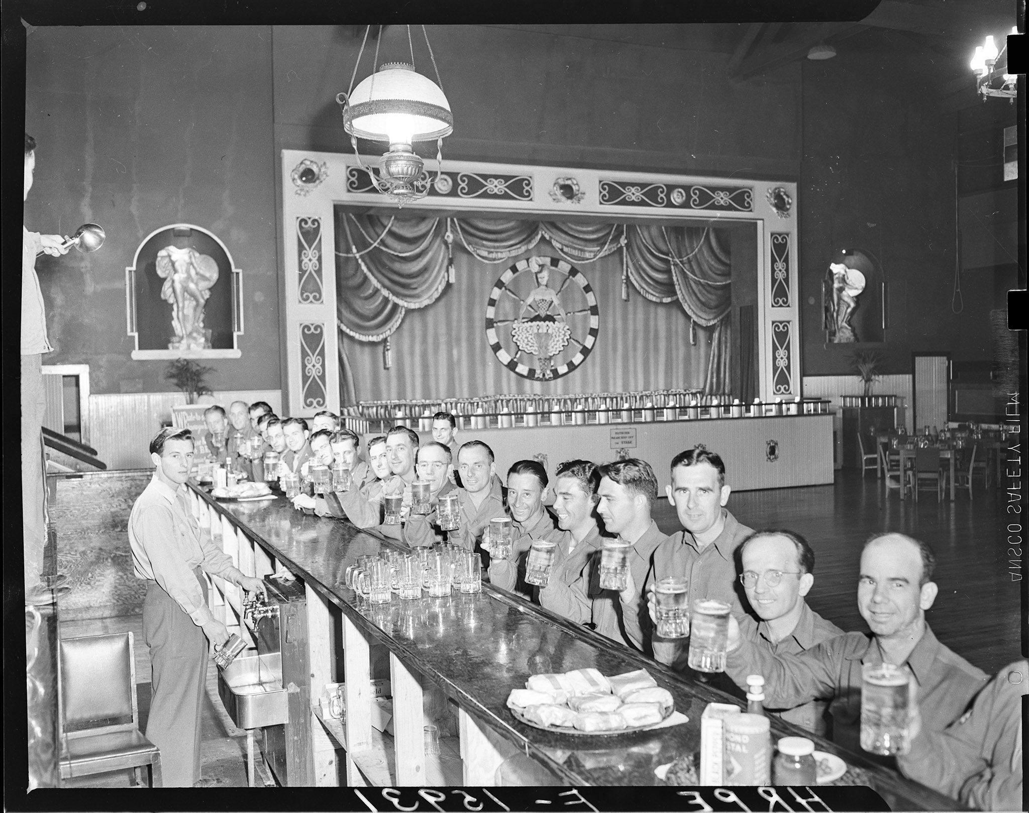 Discharged soldiers sitting along the counter, beers in hand, smiling for the camera.