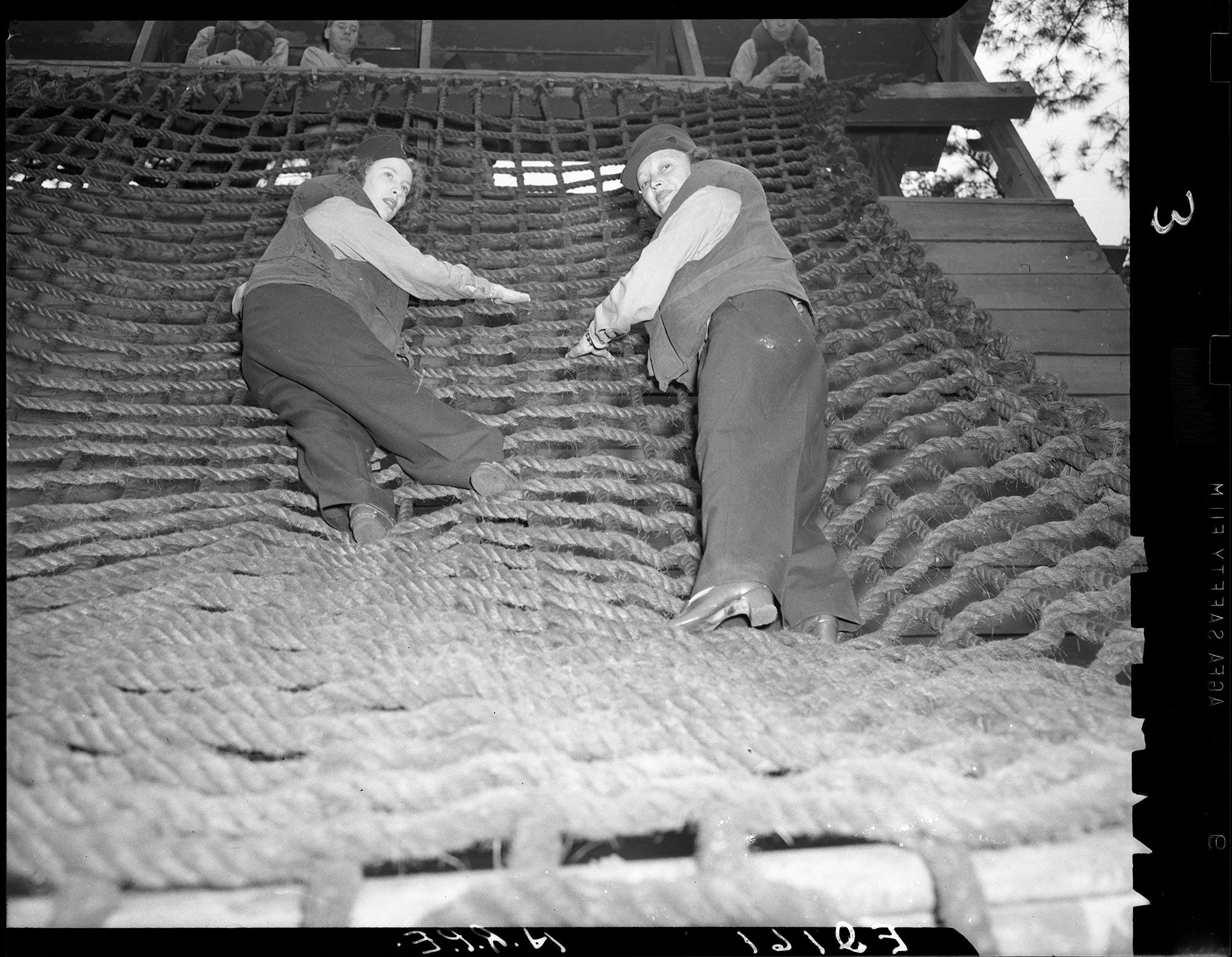 Katharine Cornell, right, and actress Elaine Perry climbing a rope wall.