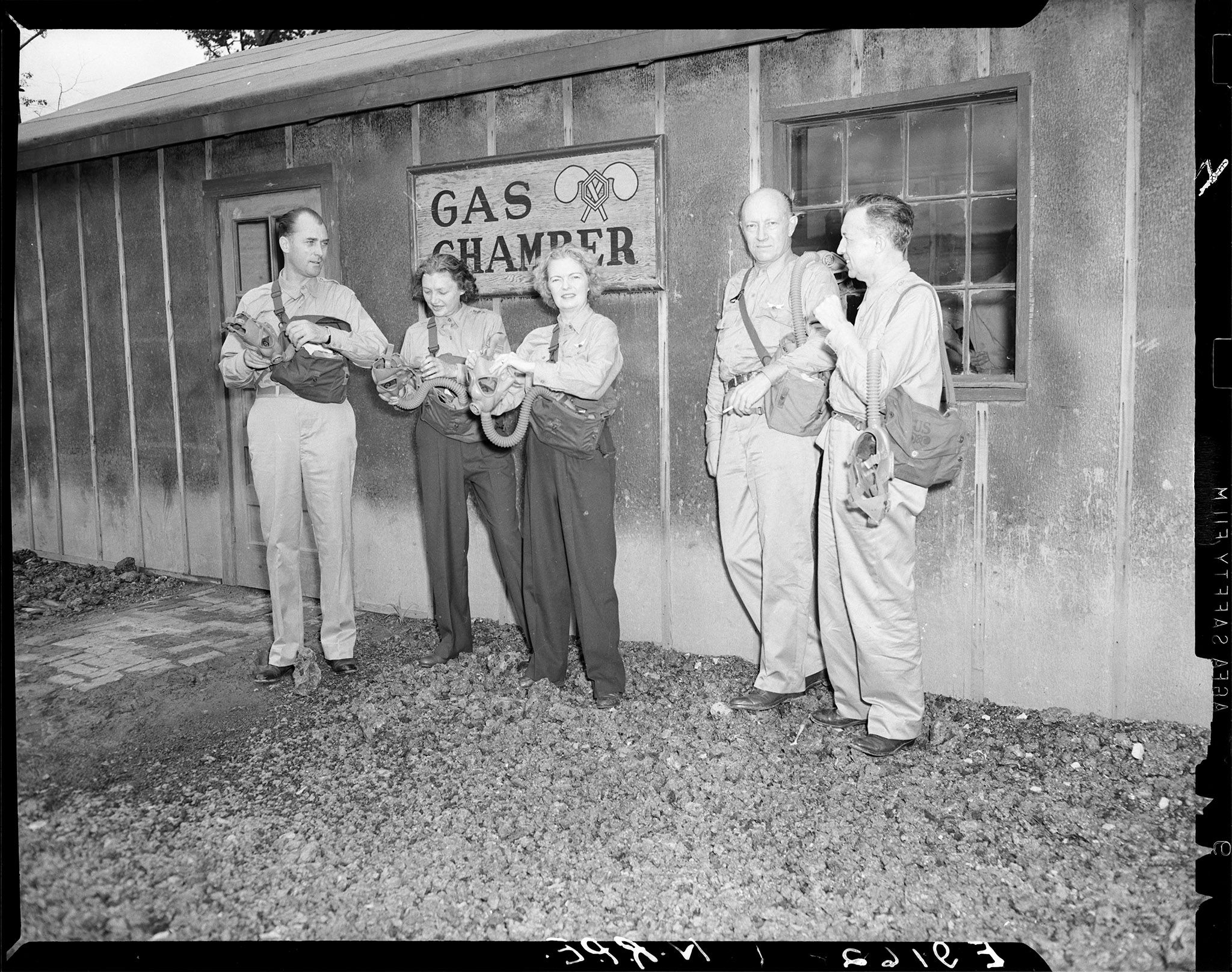Katharine Cornell, second from left, and Margalo Gillmore, center, practice a gas mask drill by stepping into a gas chamber.