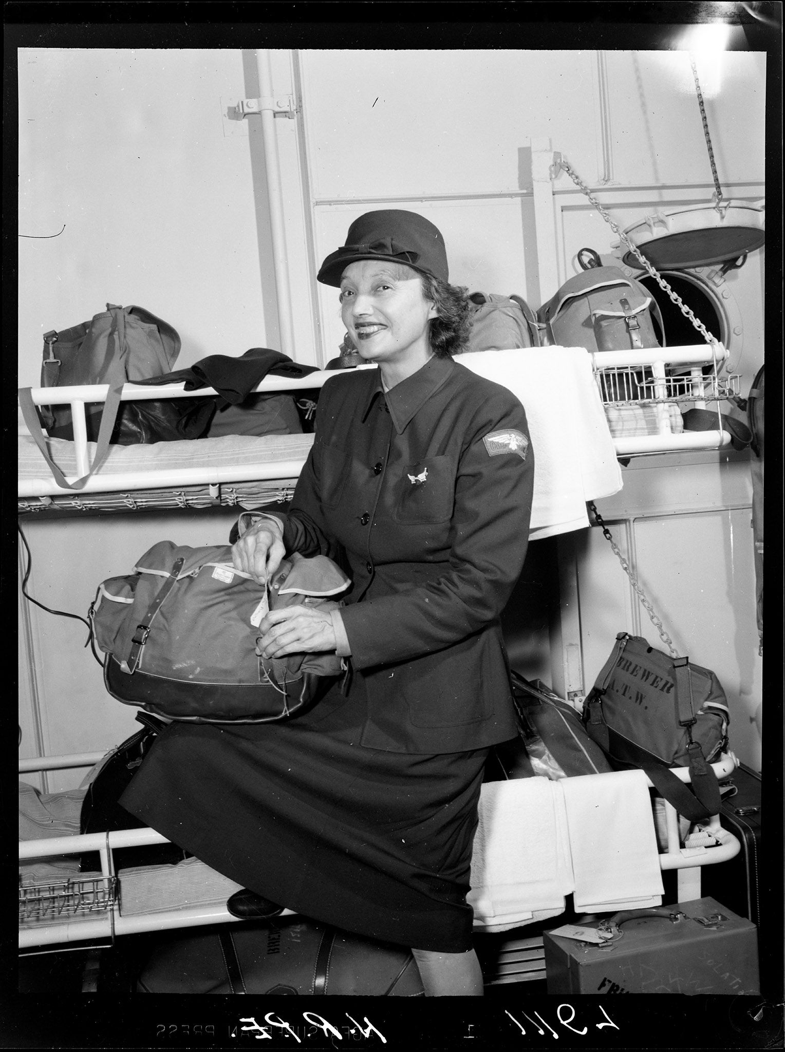 Katharine Cornell unpacks bags in a stateroom in the Hampton Roads Port of Embarkation.