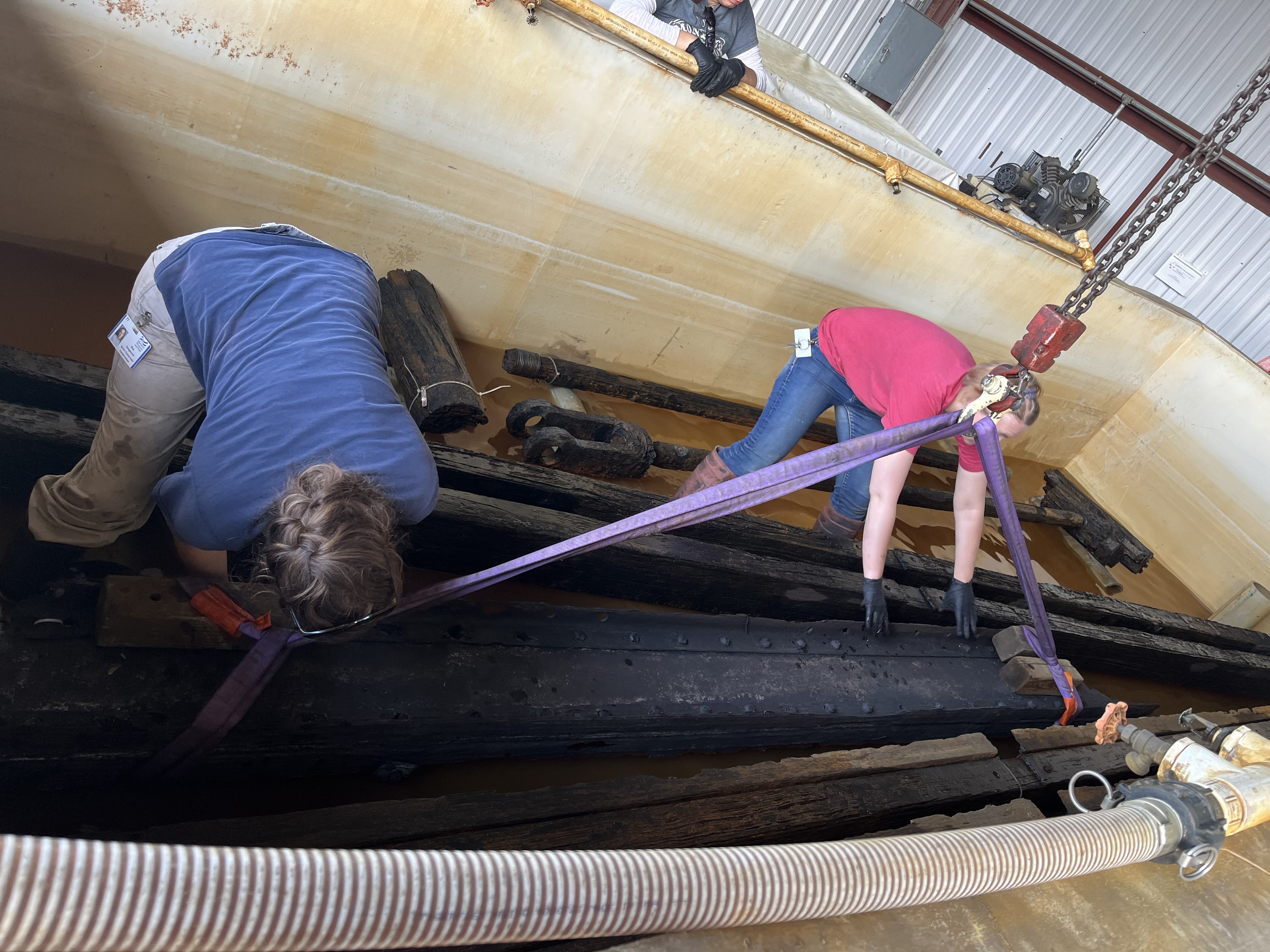 This tank holds some of our longest objects! Here you see Senior Conservator Elsa Sangouard and Assistant Archaeological Conservator Olivia Haslam rigging up one of the gun carriage rails (accession number MNMS-2001-003-241A) to be lifted out of the tank via crane.