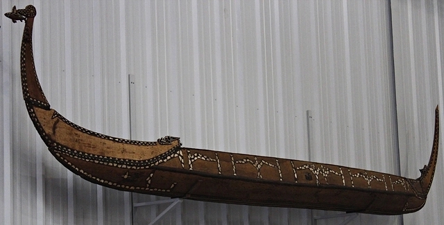 Image of long, brown boat on a wall.