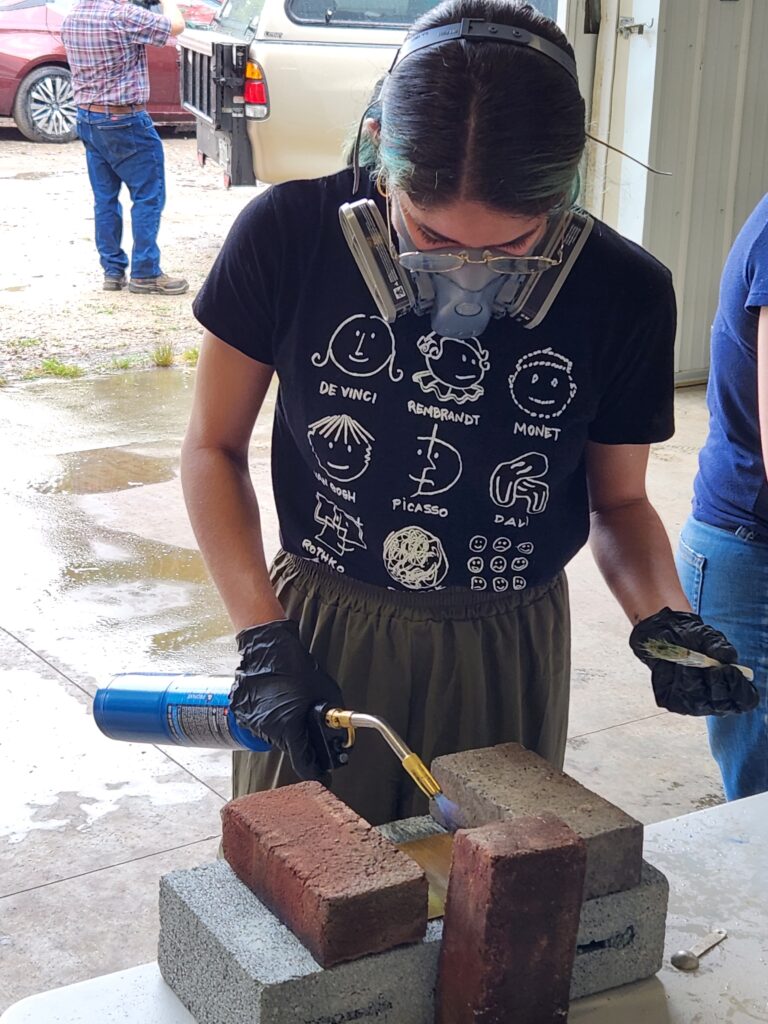 Image of Intern Marimar working in a patina at the workshop with Andrew Baxter.