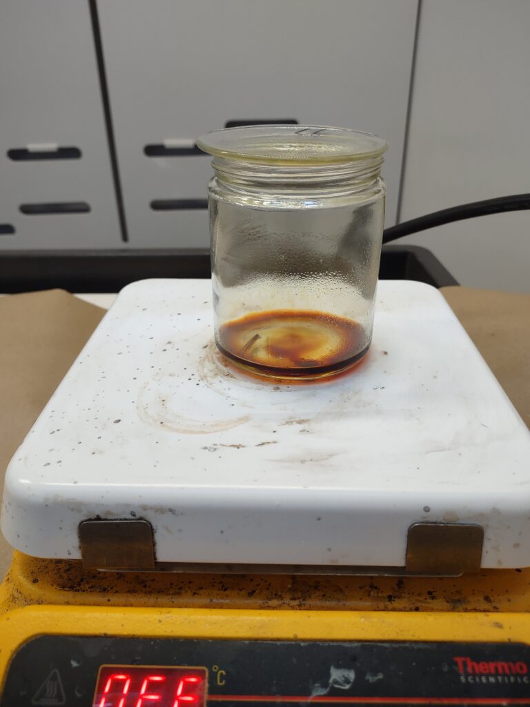 mage of a jar filled with melted resin sitting on a white hotplate. The resin is a deep orange/brown.