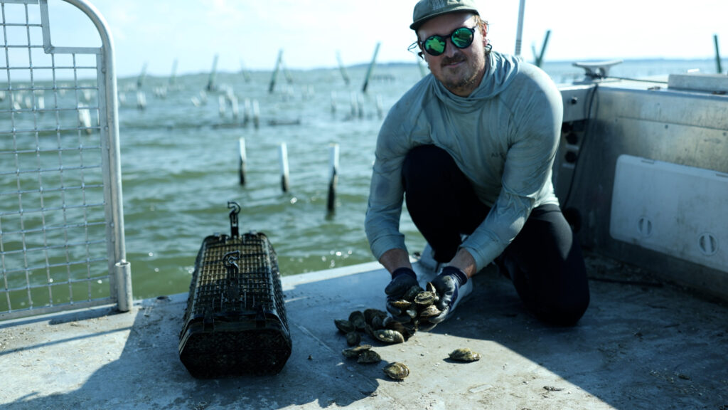 Corey Harris is shown on the deck holding oysters next to one of the baskets.