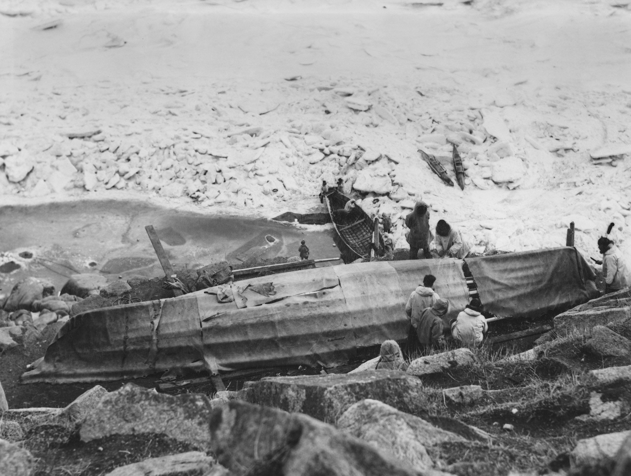 Looking down on Alaskan natives covering umiak with skin.