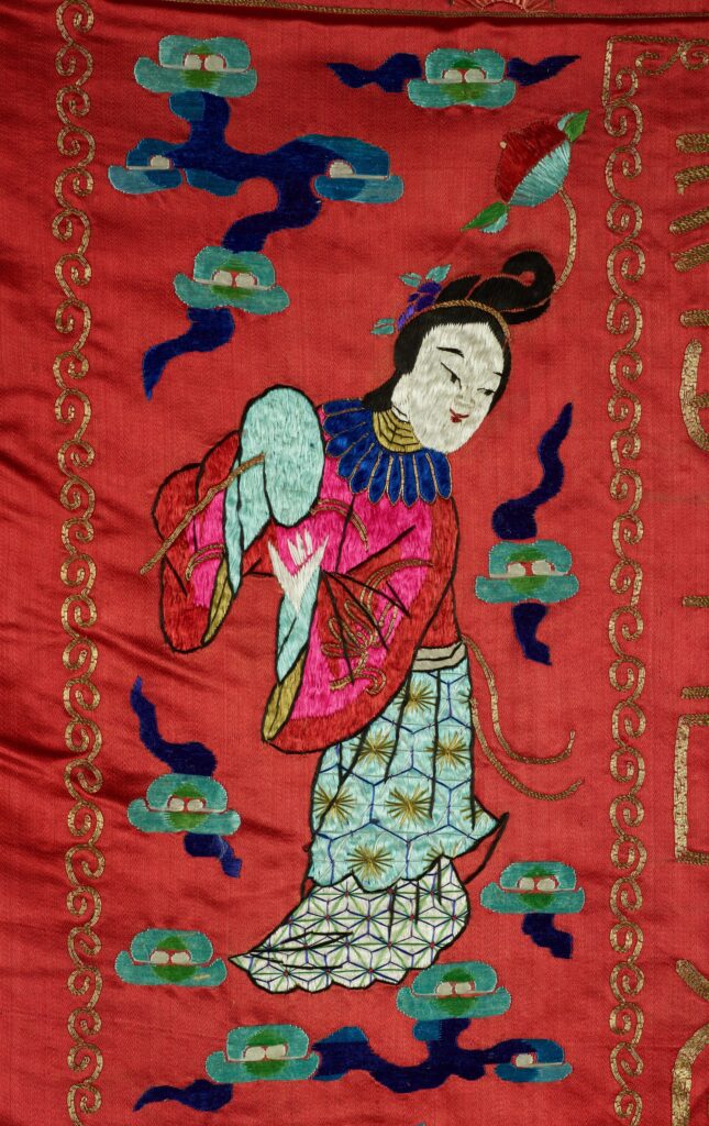 A figure of a smiling female surrounded by flowers on the tapestry.