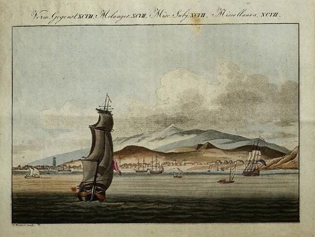 Several vessels sail toward a town on the beach with rising above the town.