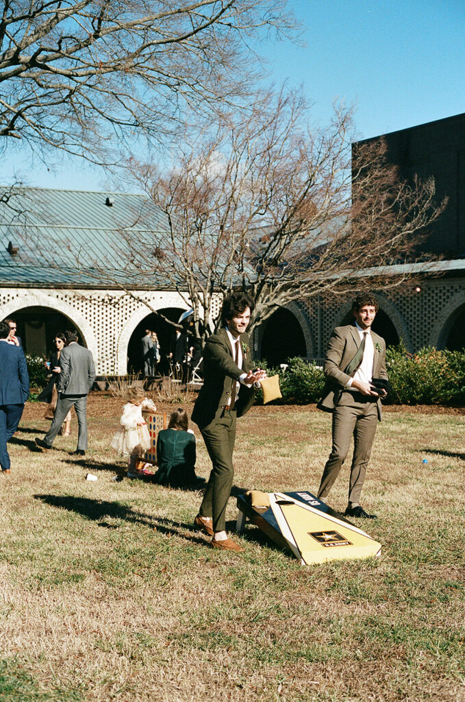 People stand on the grass playing games in formal clothing.