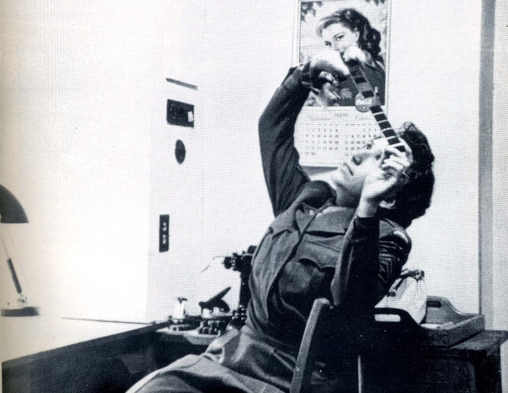 A woman in uniform observes a film strip.