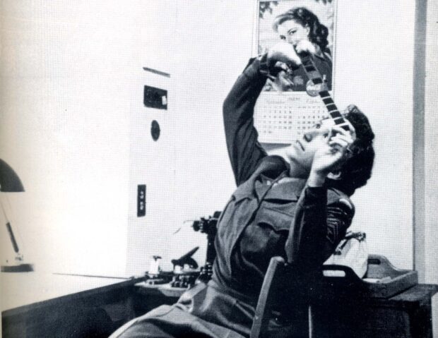 A woman in uniform observes a film strip.