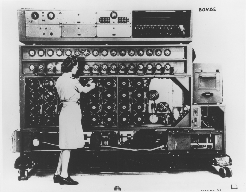 A black and white image of a woman standing in front of a large machine.