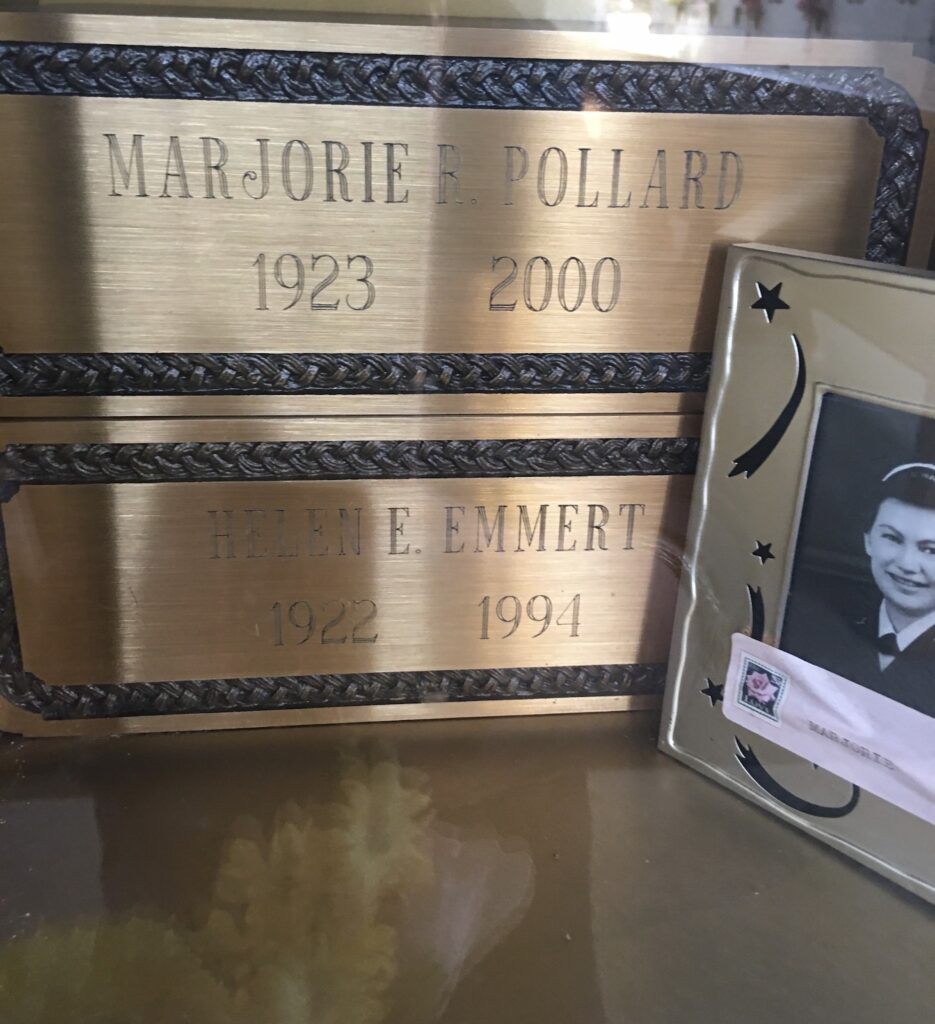 Two plaques with names on them sit beside a framed picture of a smiling woman in uniform.