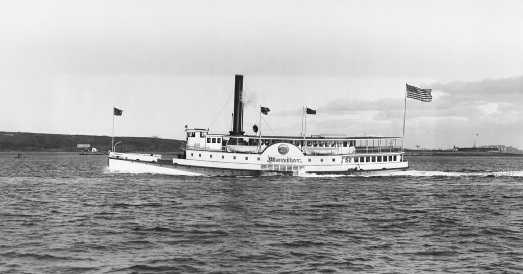 Black and white photograph of a side-wheel steamer boat in the water.
