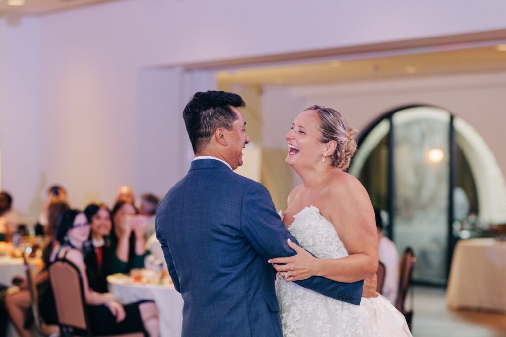 Bride and groom smiling while dancing together.