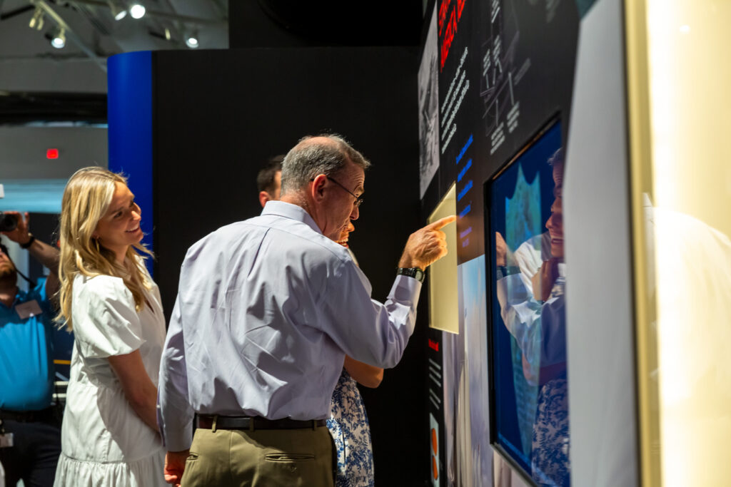 People looking and reading the displays in The Speed and Innovation in The America's Cup gallery.