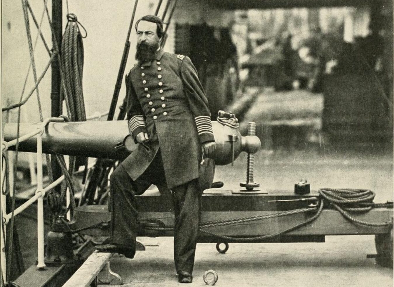 Black and white image of David Dixon Porter. He is leaning on a canon, looking off to the side.
