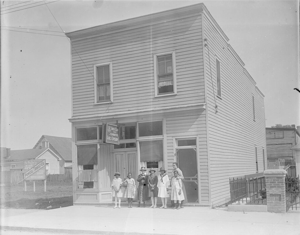 A black and white photo of girls and women in front of a building.