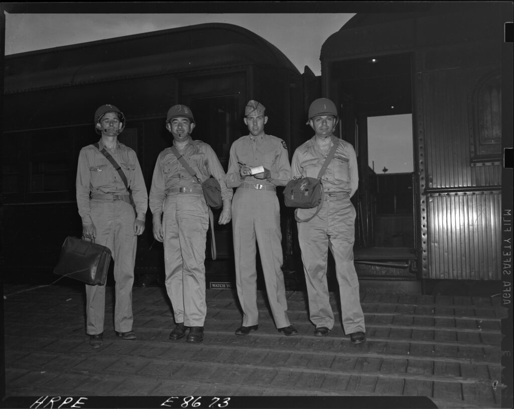 black and white photo of four men in army uniforms looking into the camera