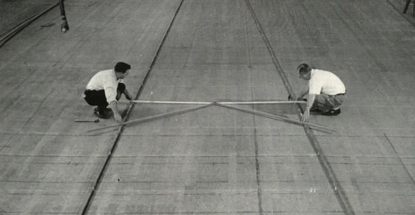 black and white picture of twho men holding long objects while kneeling